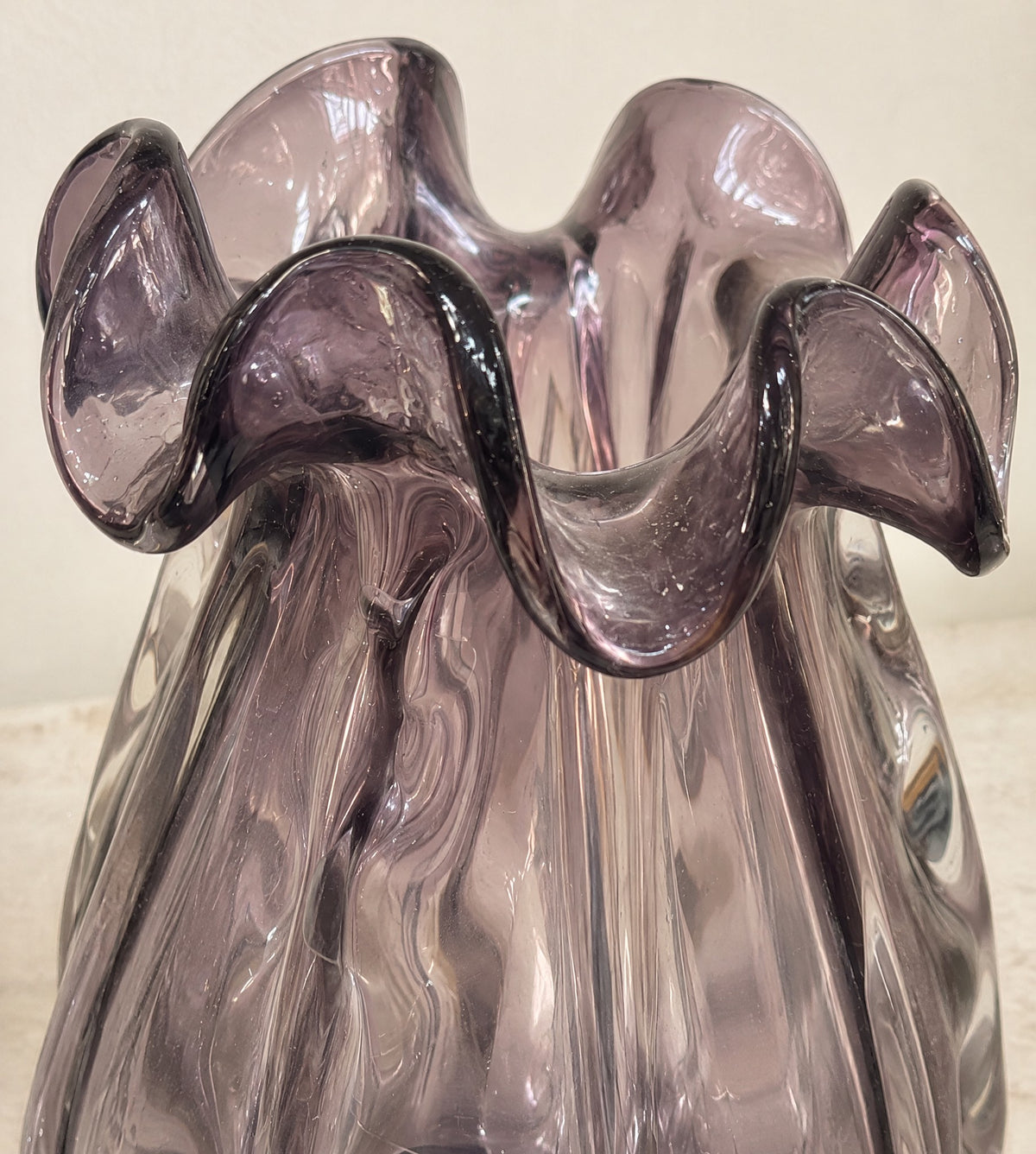 Close-up of the folded ruffled rim of the small amethyst glass vase