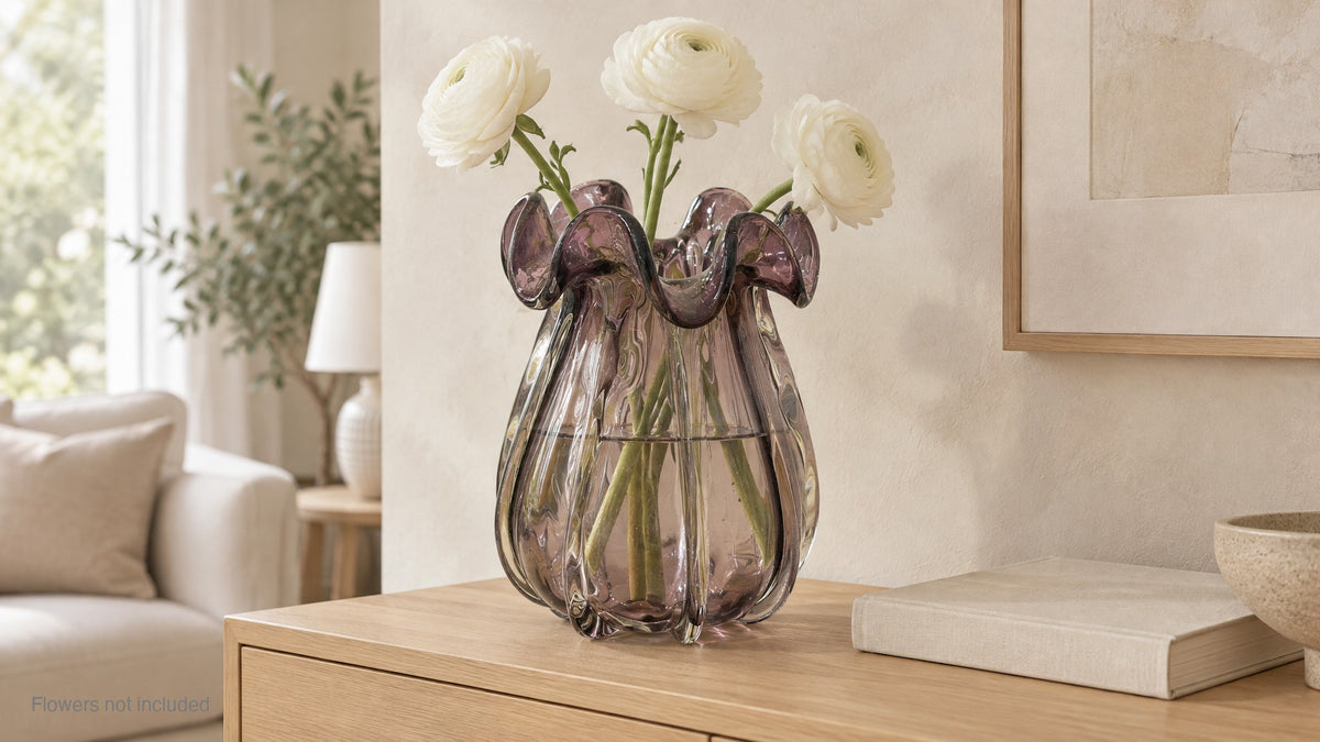 Small amethyst glass vase holding white ranunculus on a pale oak sideboard; flowers not included