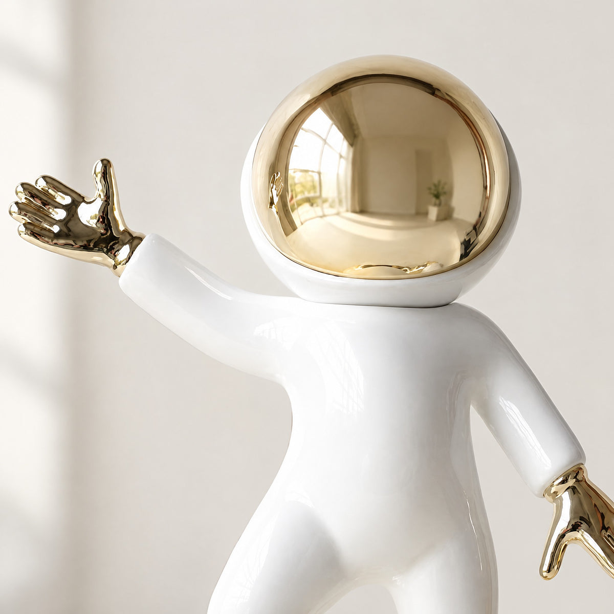 Close-up of the white resin astronaut's helmet with a mirror-gold visor and a raised gold-plated glove