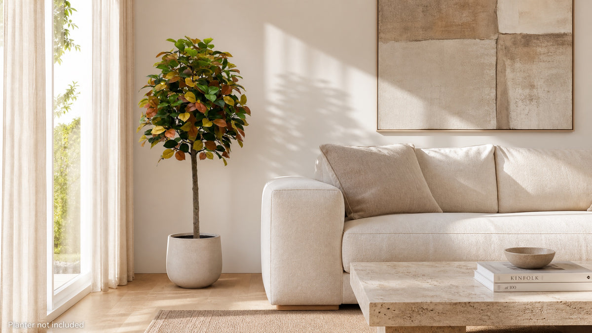 Autumn camellia artificial tree in a stone planter beside a linen sofa; planter not included