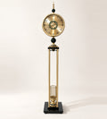 Barrel & Brass Time Tower floor clock, 161 cm, in brushed gold with a wine bottle cage and a black crystal-glass base, on an ivory background