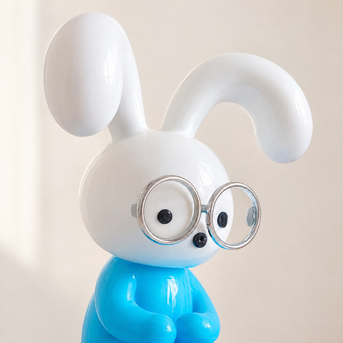 Close-up of the glossy resin bunny's white head, long ears and round silver-rimmed glasses above its sky-blue body
