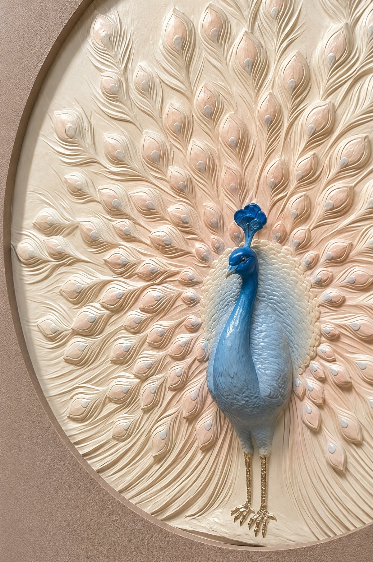 Close view of the hand-finished relief: the raised blue peacock with gold legs among sculpted ivory and blush feathers
