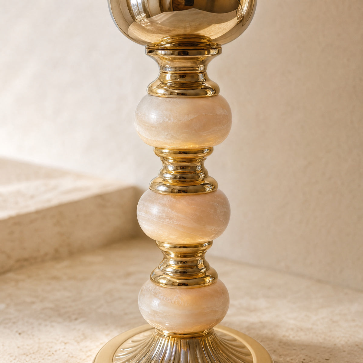 Close-up of the three pale onyx spheres and polished gold collars on the candle holder stem