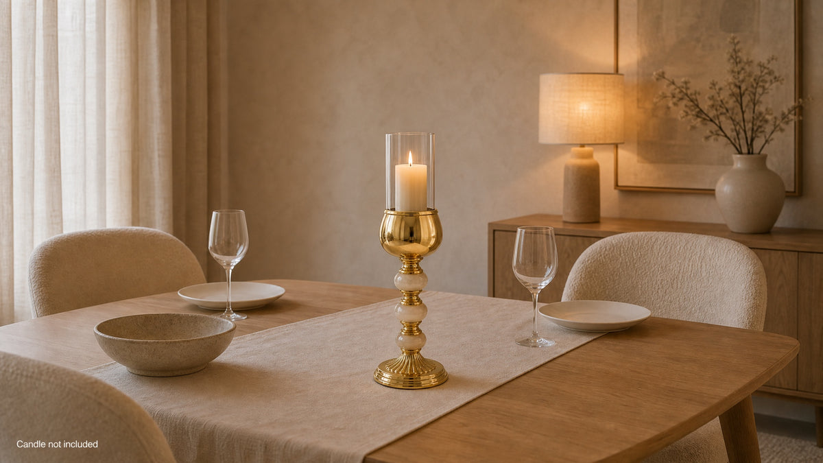 Onyx and gold hurricane candle holder with a lit pillar candle on a dining table runner; candle not included