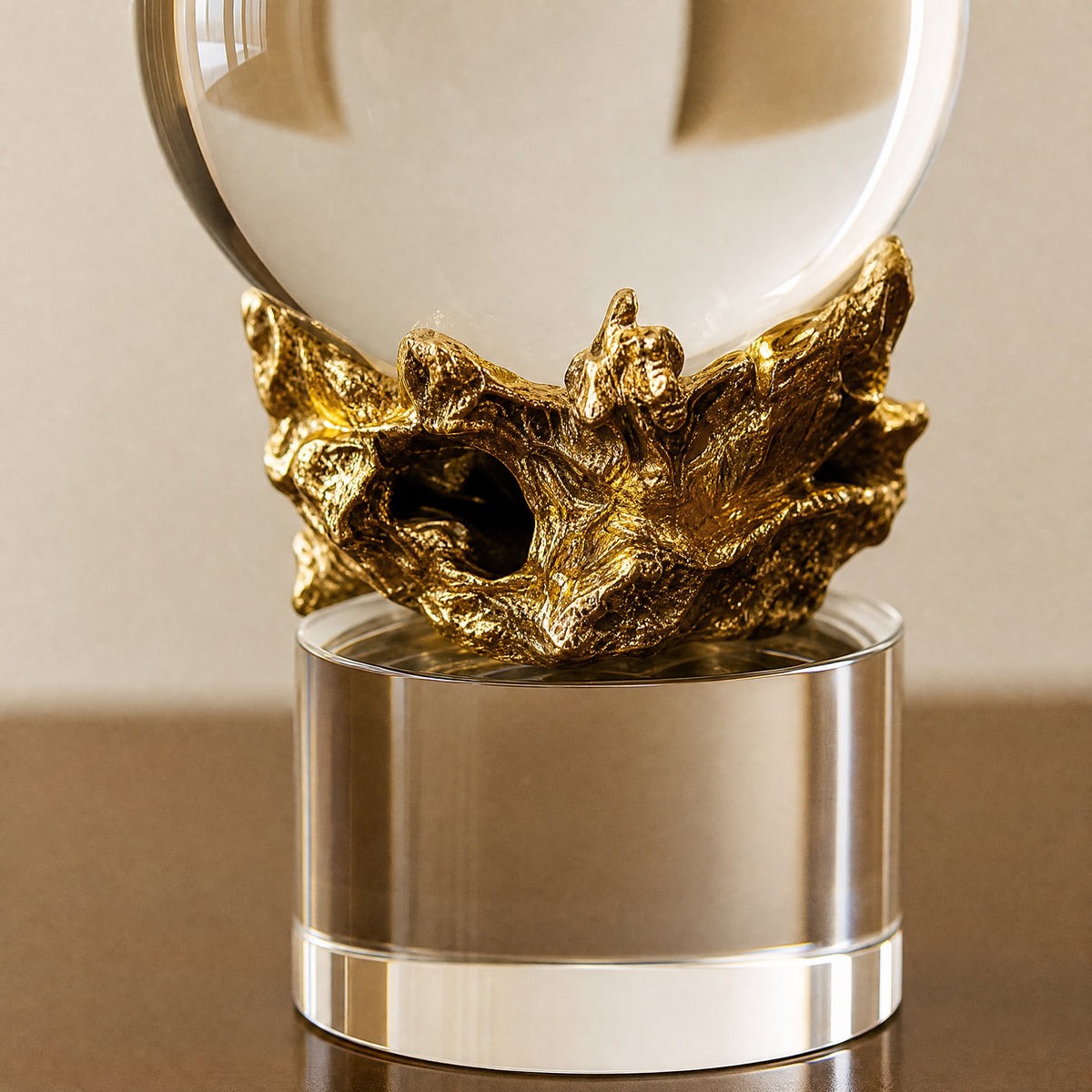 Close-up of the sculpted gold-finish metal cradle holding the crystal sphere above a clear crystal column