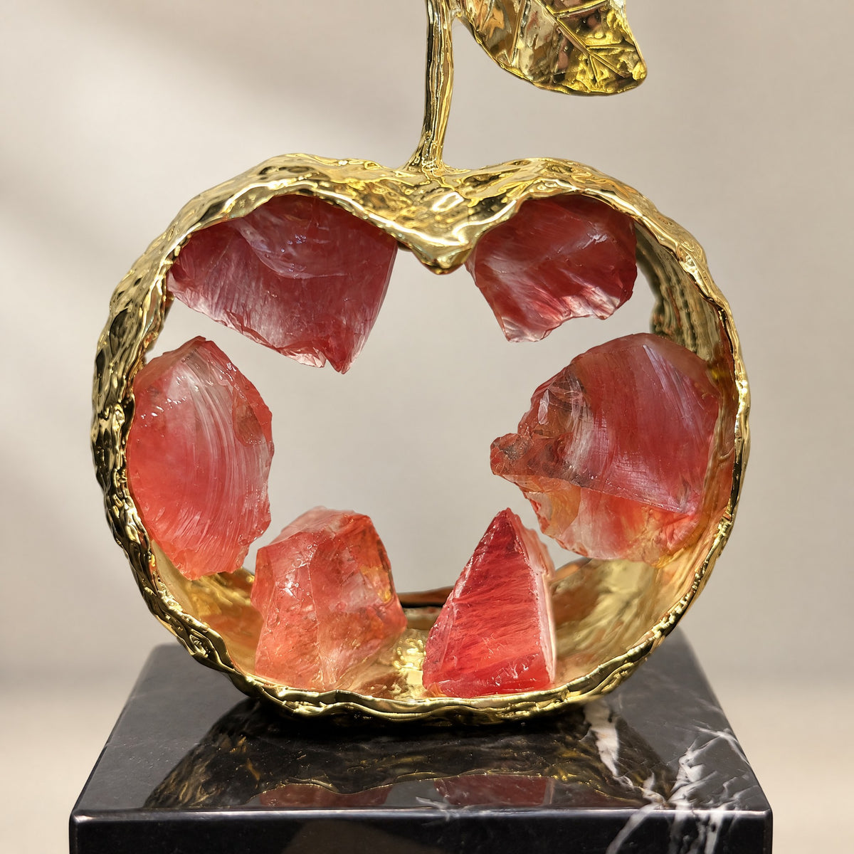 Close-up of raw red K9 crystal chunks inside the hammered gold apple shell