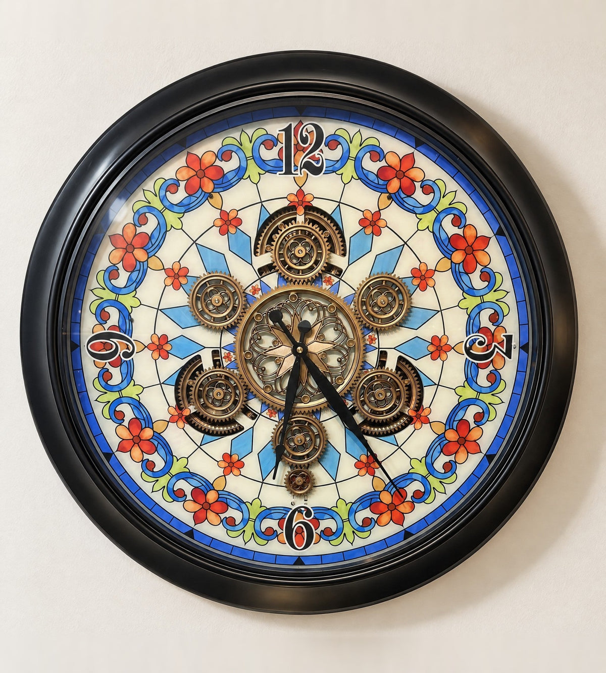 Garden Aura wall clock with a stained-glass dial and gold gears in a black metal frame, front view on an ivory wall