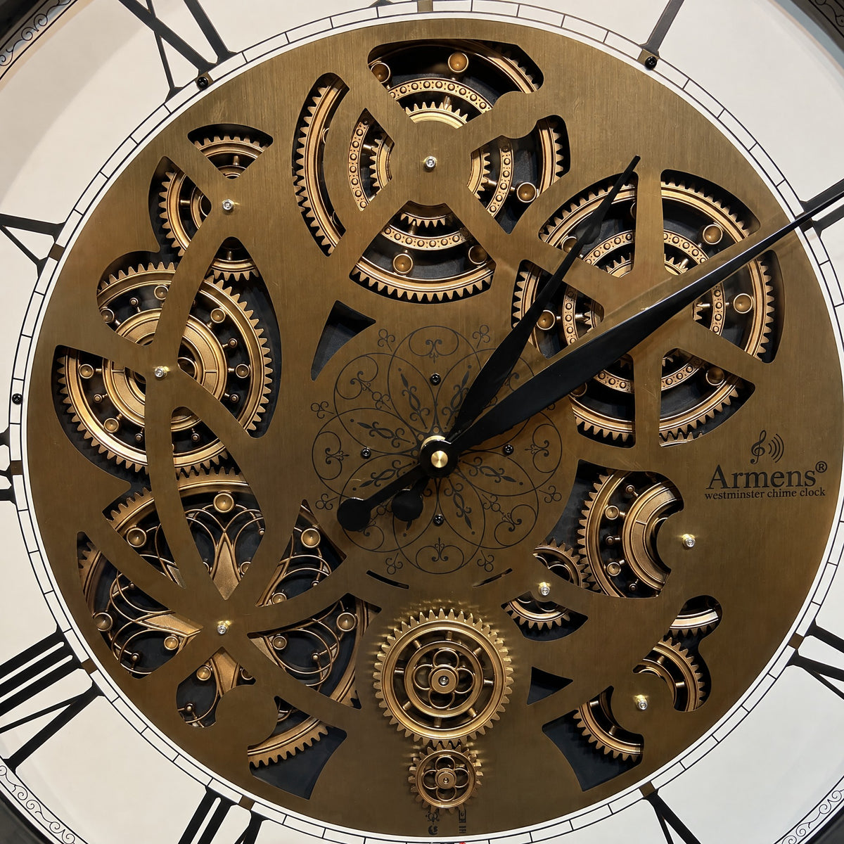 Close-up of the Obsidian Gear wall clock: laser-cut bronze-gold plate, gold gears behind it and an engraved filigree rosette
