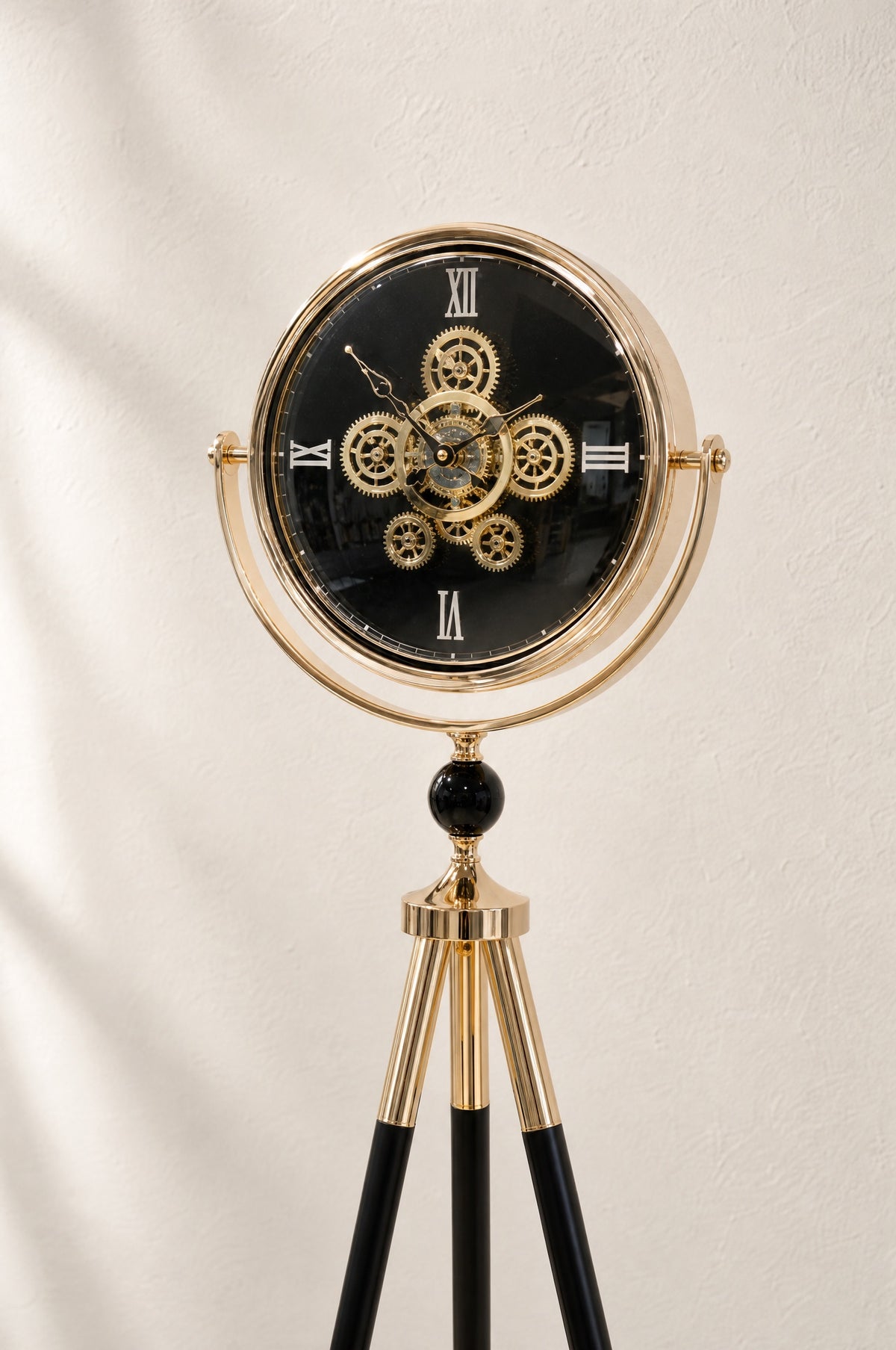 Close view of the Shadow Line clock face: exposed gold gears on a black dial in a tilting gold-finish ring above a black sphere