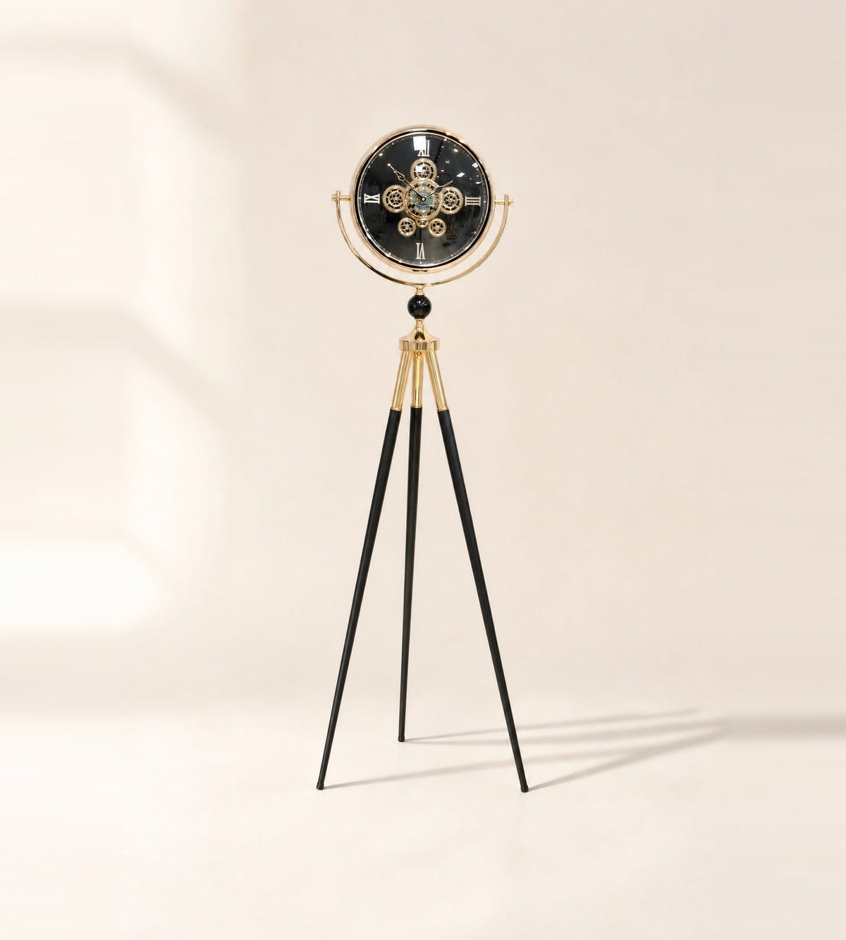 Shadow Line tripod floor clock with black moving-gear dial in a gold-finish ring on slim black legs
