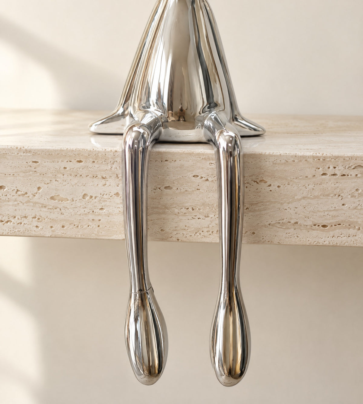 Close-up of the chrome bunny's long legs and feet hanging over a travertine edge