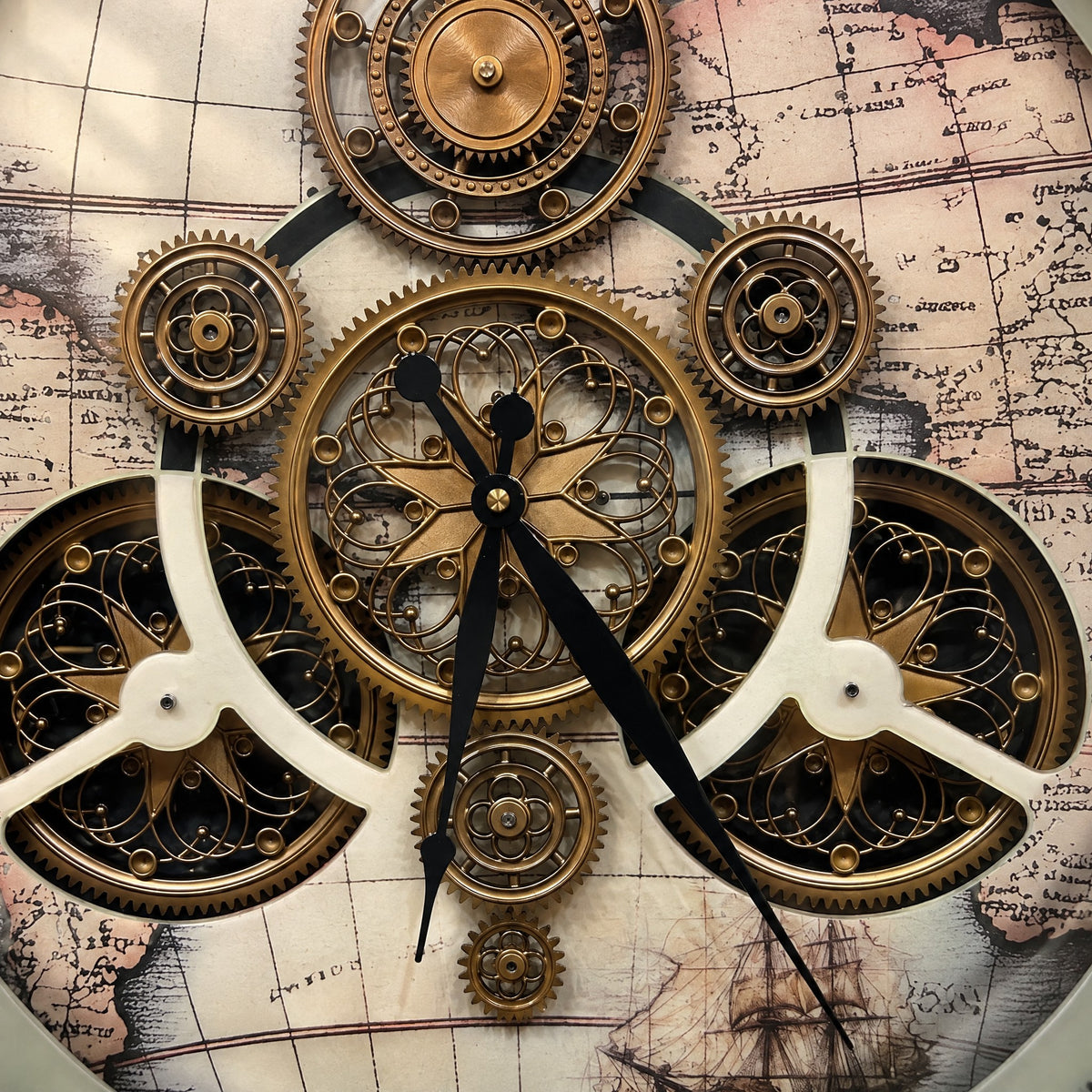 Close-up of the Traveler's Gear wall clock: gold gears and cream bridges over a printed antique map