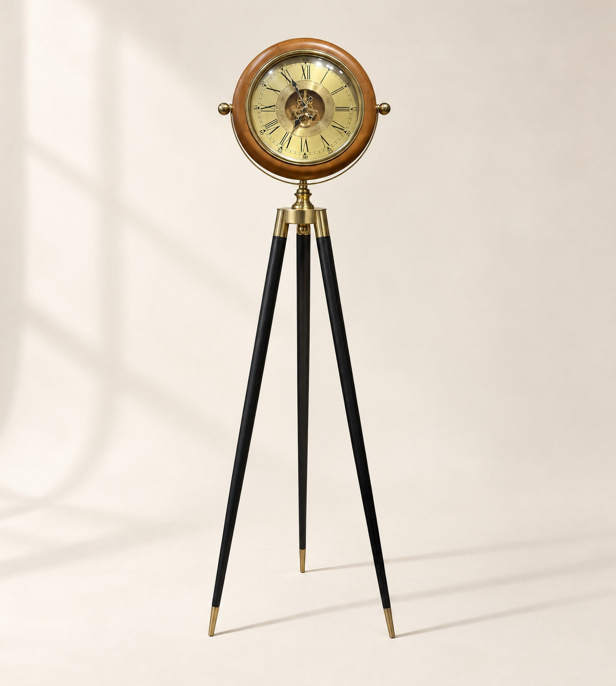 Wood and brass tripod floor clock with a gold gear dial, standing on a plain ivory backdrop
